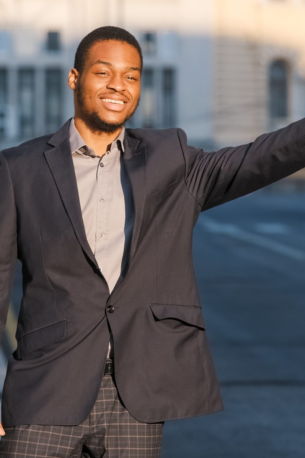 Modern businessman or manager gesturing to give signal to car driver on the street in big city. Taxi