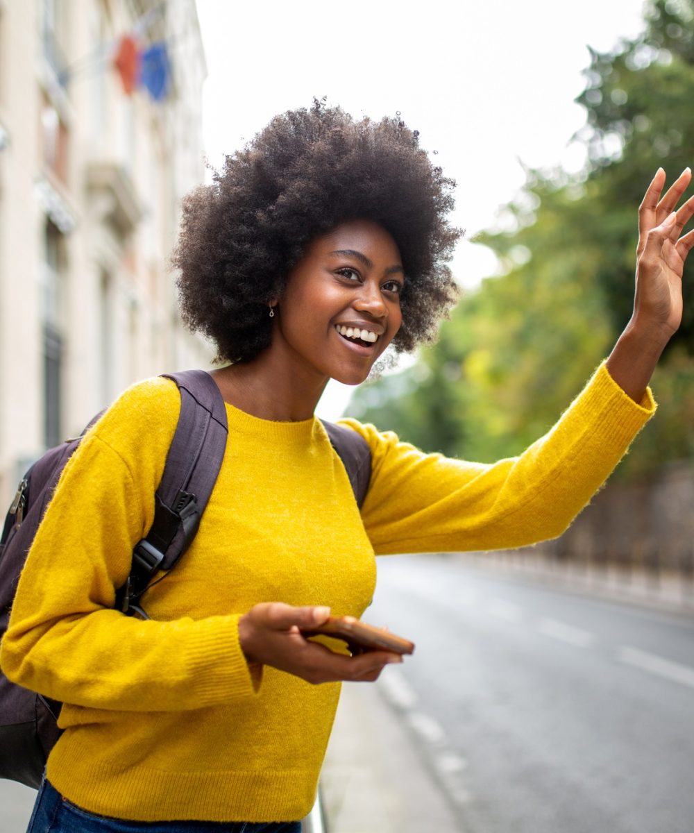 Young african woman calling a taxi in the city